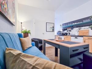 a living room with a blue couch and a kitchen at Alpha Apartments in Herdecke