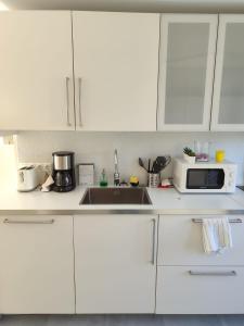 eine weiße Küche mit Spüle und Mikrowelle in der Unterkunft Pinos de Calahonda duplex in Sitio de Calahonda + 24 Fotos