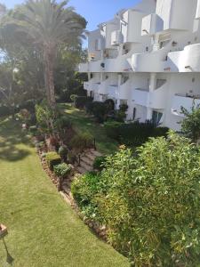 an apartment building with a palm tree and plants at Pinos de Calahonda duplex in Sitio de Calahonda