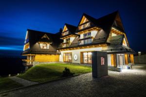 a large house with a black roof at night at Hotel Kopieniec Fizjo- Med & SPA in Murzasichle