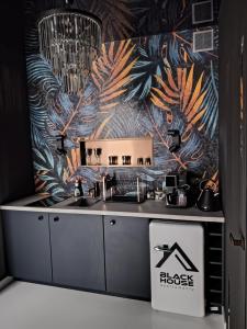 a kitchen with a sink and a tropical wallpaper at Black House A in Radom