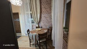 a dining room table with chairs and a brick wall at Suite Roma 3 in Velingrad