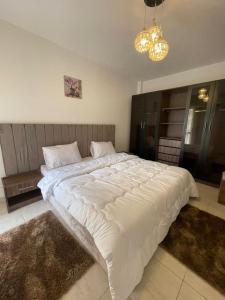 ein großes weißes Bett in einem Schlafzimmer mit einem Kronleuchter in der Unterkunft Family 2 bedrooms B6 group 62 in Madinaty