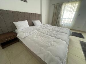 ein großes Bett mit weißer Bettwäsche und Kissen im Schlafzimmer in der Unterkunft Family 2 bedrooms B6 group 62 in Madinaty