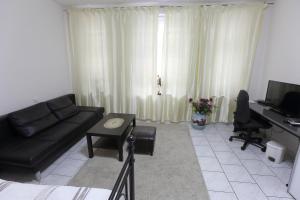 a living room with a black couch and a desk at City Apartment 1 in Brühl