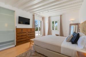a bedroom with a large bed and a television at Myconian Platinum Senior & Deluxe Villas in Kalafatis +96 photos