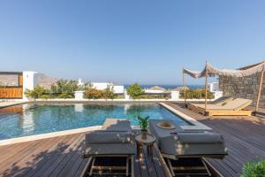 a swimming pool with chaise lounge chairs on a wooden deck at Myconian Platinum Senior & Deluxe Villas in Kalafatis