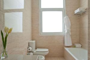 a bathroom with a toilet and a window and a sink at NH City Buenos Aires in Buenos Aires