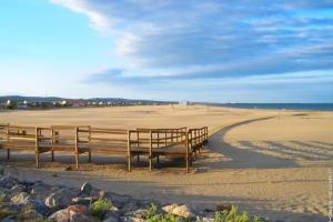 two benches sitting on a beach near the ocean at Plage des Chalets in Gruissan