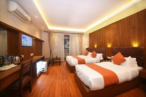 una camera d'albergo con due letti e una televisione di Hotel Mums Home a Kathmandu