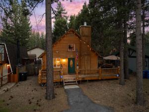 una cabaña de troncos en el bosque con árboles en Cozy mountain cabin, Hot Tub, BBQ, Games by MariamsBnb, en Big Bear City
