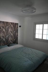 a bedroom with a bed with a blanket and a window at Villa Orchidée- au coeur du centre-ville in LʼEntre-Deux