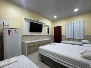 a room with two beds and a flat screen tv at Hotel Maracá in Boa Vista