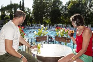a man and a woman sitting at a table with drinks at Hotel La Diga Altomincio in Valeggio sul Mincio