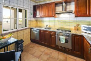 a kitchen with wooden cabinets and a stainless steel oven at 09 Terracos de Benagil - Casa do Pato in Benagil