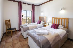 a bedroom with two beds and a chair and a window at 09 Terracos de Benagil - Casa do Pato in Benagil +14 photos