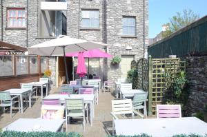 una fila di tavoli e sedie con ombrellone di Davitts Guesthouse a Kenmare