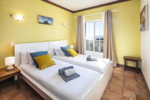 two beds in a room with a window at 31 Terracos de Benagil - Casa Bobo in Benagil +24 photos