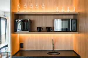 a kitchen with a sink and a microwave and glasses at Cyclinn Brooklin Novo in São Paulo