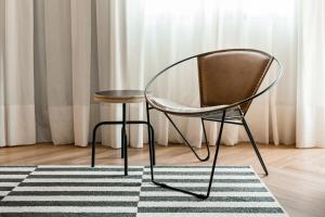a chair and a stool in front of a window at Cyclinn Brooklin Novo in São Paulo