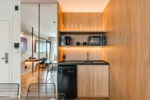 a kitchen with a black refrigerator and wooden cabinets at Cyclinn Brooklin Novo in São Paulo