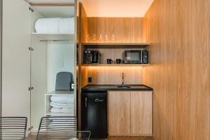 a small kitchen with a black refrigerator and a microwave at Cyclinn Brooklin Novo in São Paulo
