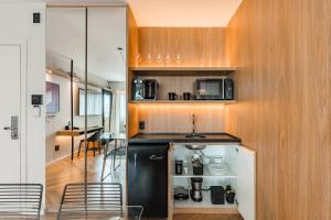 a kitchen with a black refrigerator and wooden cabinets at Cyclinn Brooklin Novo in São Paulo +25 photos