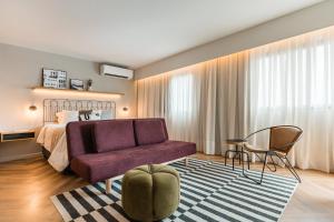 a bedroom with a bed and a purple couch at Cyclinn Brooklin Novo in São Paulo