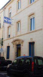 un bâtiment avec une voiture garée devant lui dans l'établissement Hotel de France, à Narbonne