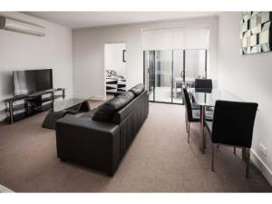 sala de estar con sofá de cuero negro y mesa en The Star Apartments, en Newcastle