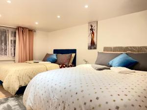 two beds in a bedroom with blue and white at Shepherds House - 3 bedroom in Goodmayes