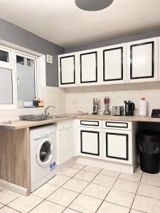 a kitchen with white cabinets and a washing machine at Shepherds House - 3 bedroom in Goodmayes +14 photos