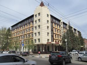 biały budynek z samochodami zaparkowanymi na parkingu w obiekcie Bogemia Hotel on Vavilov Street w mieście Saratów