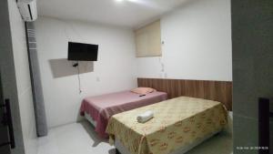 a small room with two beds and a television at Recanto Maria Pureza in Juazeiro do Norte