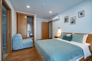a bedroom with a large bed and a blue chair at Alojamento Jasmine in São Pedro de Alva +80 photos