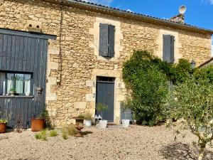 a stone house with a blue door in a yard at Ma demeure dans les vignes in Sainte-Foy-la-Longue