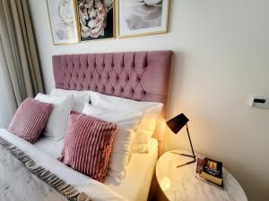 a bed with a pink headboard and a table with a lamp at Studio apartment Lora Lux - Bulevar in Sarajevo