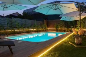 a swimming pool with umbrellas in a backyard at night at Villa Verde Royal in Kaštela