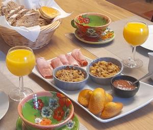 einen Tisch mit Teller mit Lebensmitteln und Gläsern Orangensaft in der Unterkunft Domaine de Bellevue Cottage en Périgord- Bergerac 5mn - Petits-déjeuners inclus - Salle d'eau privative - Parc 3ha - Parking Privé Gratuit in Lembras + 17 Fotos