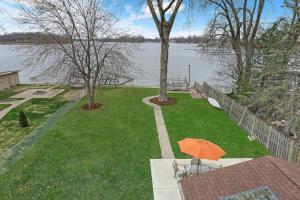 un ombrello arancione su un prato vicino all'acqua di Meyers Bay Sunset Lakefront Cottage in Fox Lake with Boat Pier a Fox Lake