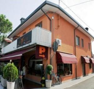 un grande edificio arancione con balcone su strada di La Casa Degli Angeli - Agli Angeli Ristorante Pizzeria a Pertegada