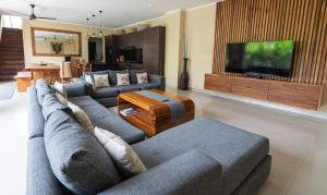 a living room with a couch and a tv at Villa Tepi Sungai - Luxury 6-BR villa, sleeps 14, 15m pool in Seminyak in Legian