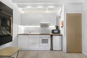 a kitchen with white cabinets and a sink and a door at Minnows Rest - North East Escapes in Seahouses