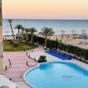 a pool at the beach with palm trees and the ocean at Elite apartment private beach Holiday Chalet Free WIFI in Hurghada