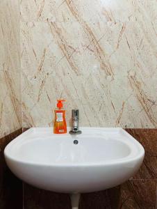 a white sink with an orange soap dispenser on it at Deluxe Rooms near Tree Park Metro station Whitefield in Bengaluru