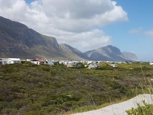 a group of houses on a hill with mountains in the background at Betty's Bay Quaint Cottage in Bettyʼs Bay
