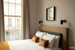 a bedroom with a bed with white pillows and a window at Bob W London Olympia in London
