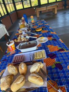 a long table with bread and other foods on it at Hotel Fazenda e Pesqueiro Pousada da Serra in Goianésia