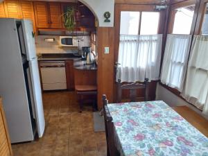 a small kitchen with a table and a refrigerator at Casa Las Mutisias in San Martín de los Andes +9 photos