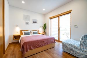 a bedroom with a bed and a chair and a window at Alojamento Jasmine in São Pedro de Alva